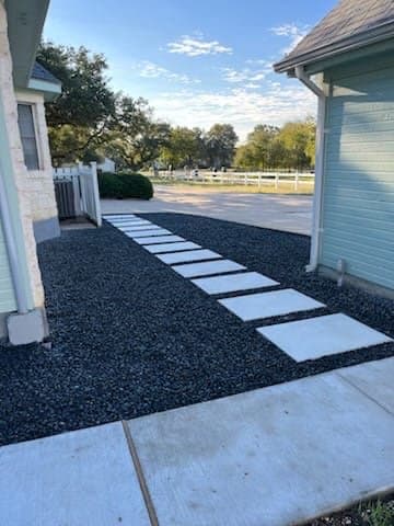 White rectangular pavers create a modern walkway through dark gravel between two houses.
