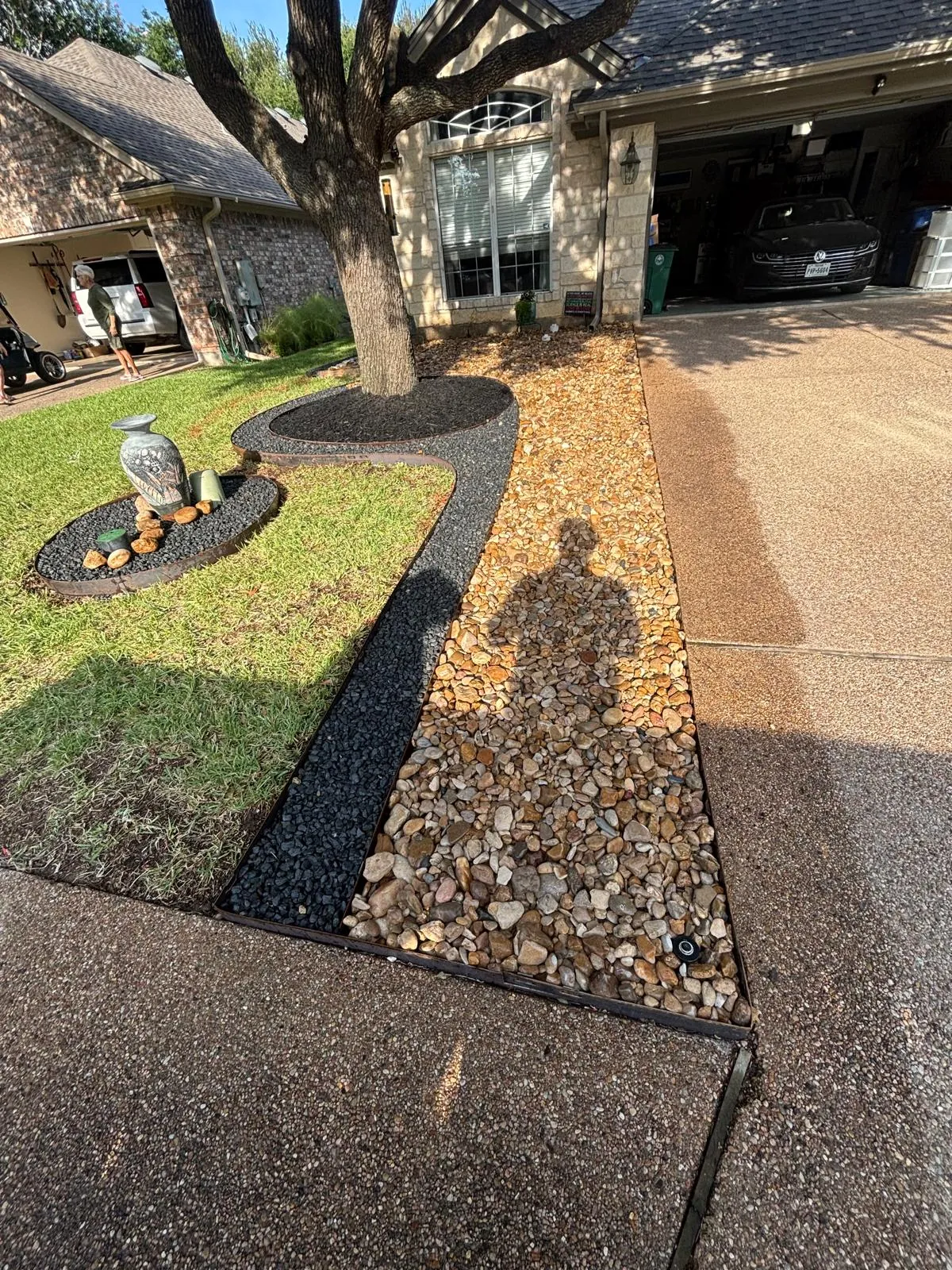 Front yard landscaping with river rock and metal edging in Austin, TX.